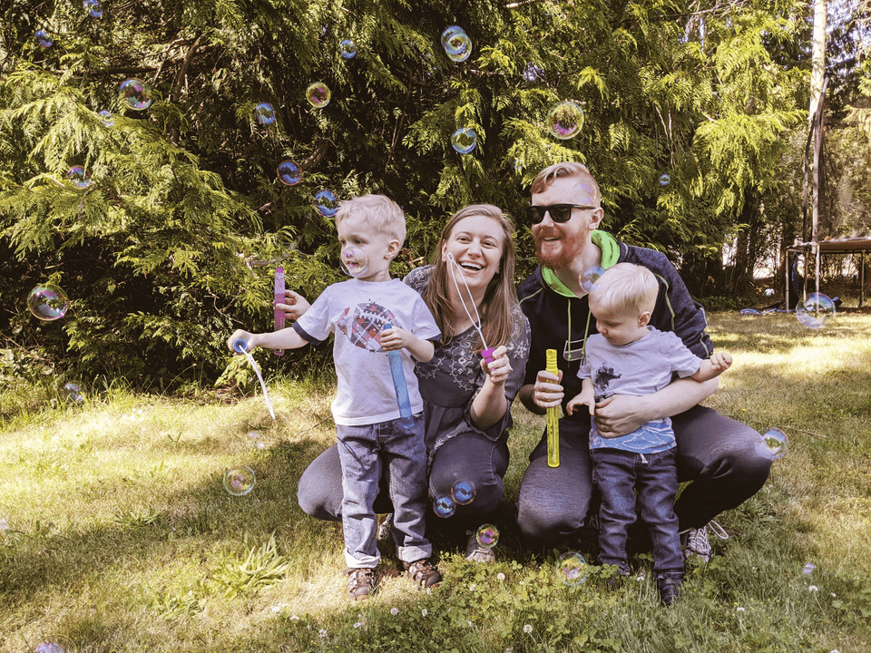 family of four blowing bubbles outside