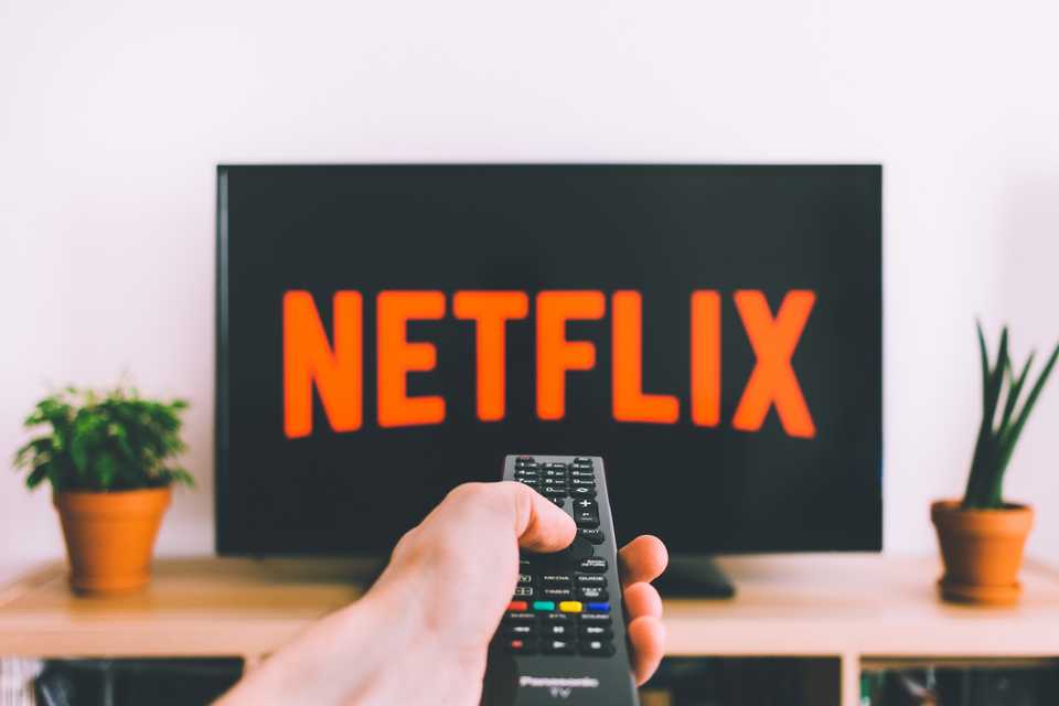 Remote control pointed at Netflix on TV