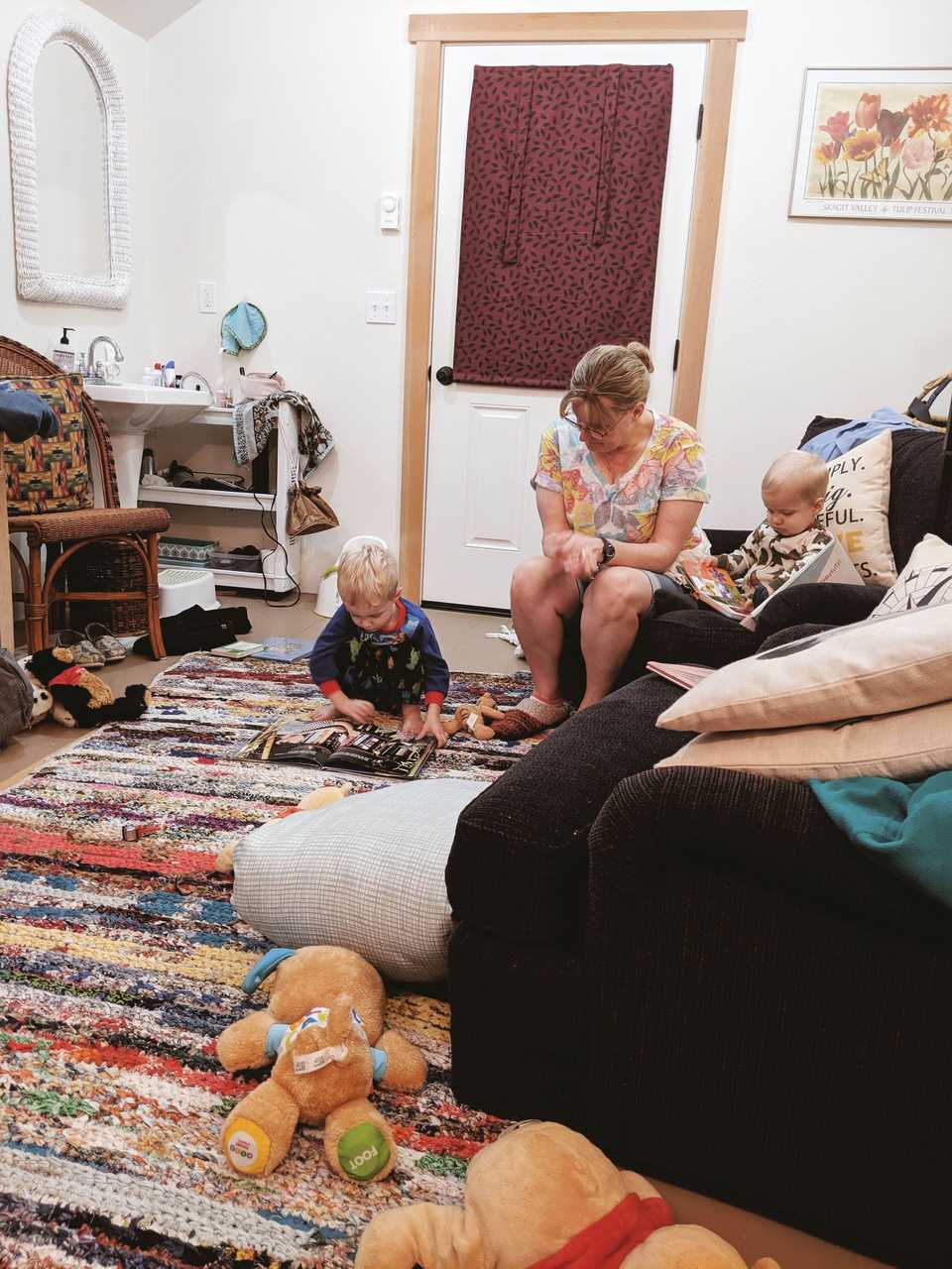 Grandma, one year old, and three year old reading books and playing in rustic barn studio home