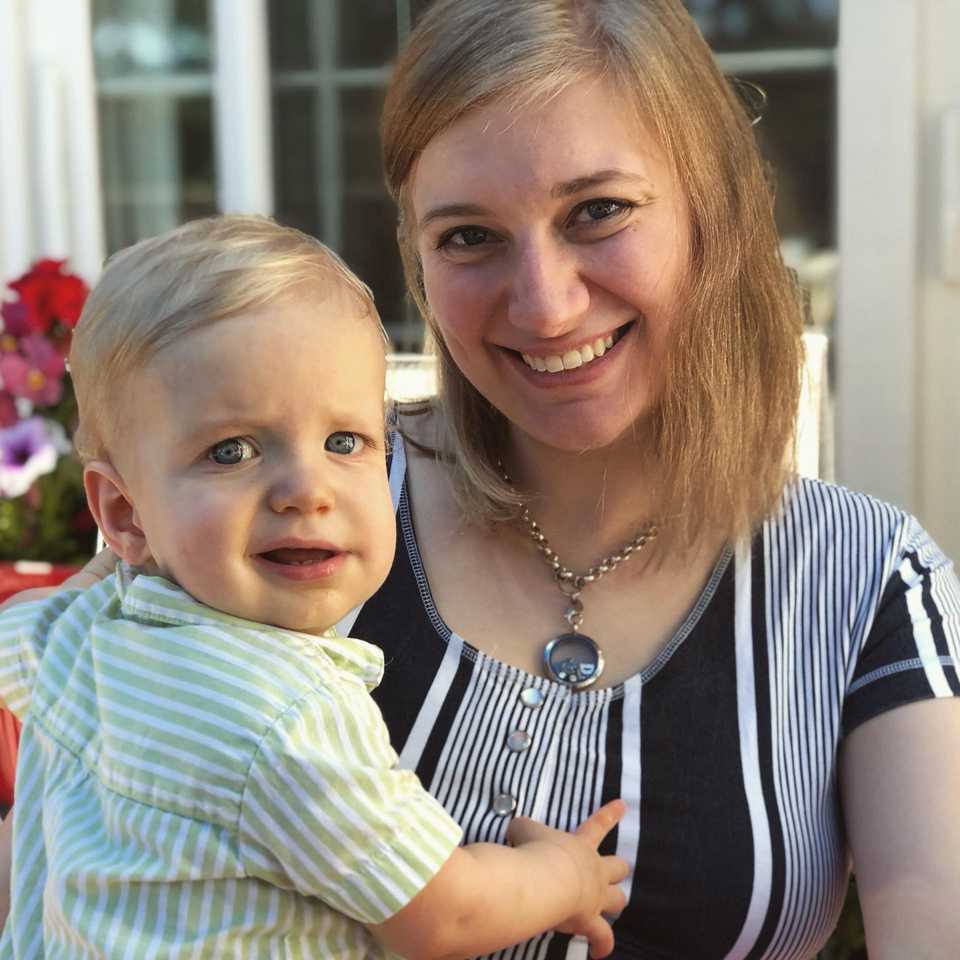 Mother holding one year old blue-eyed baby son smiling